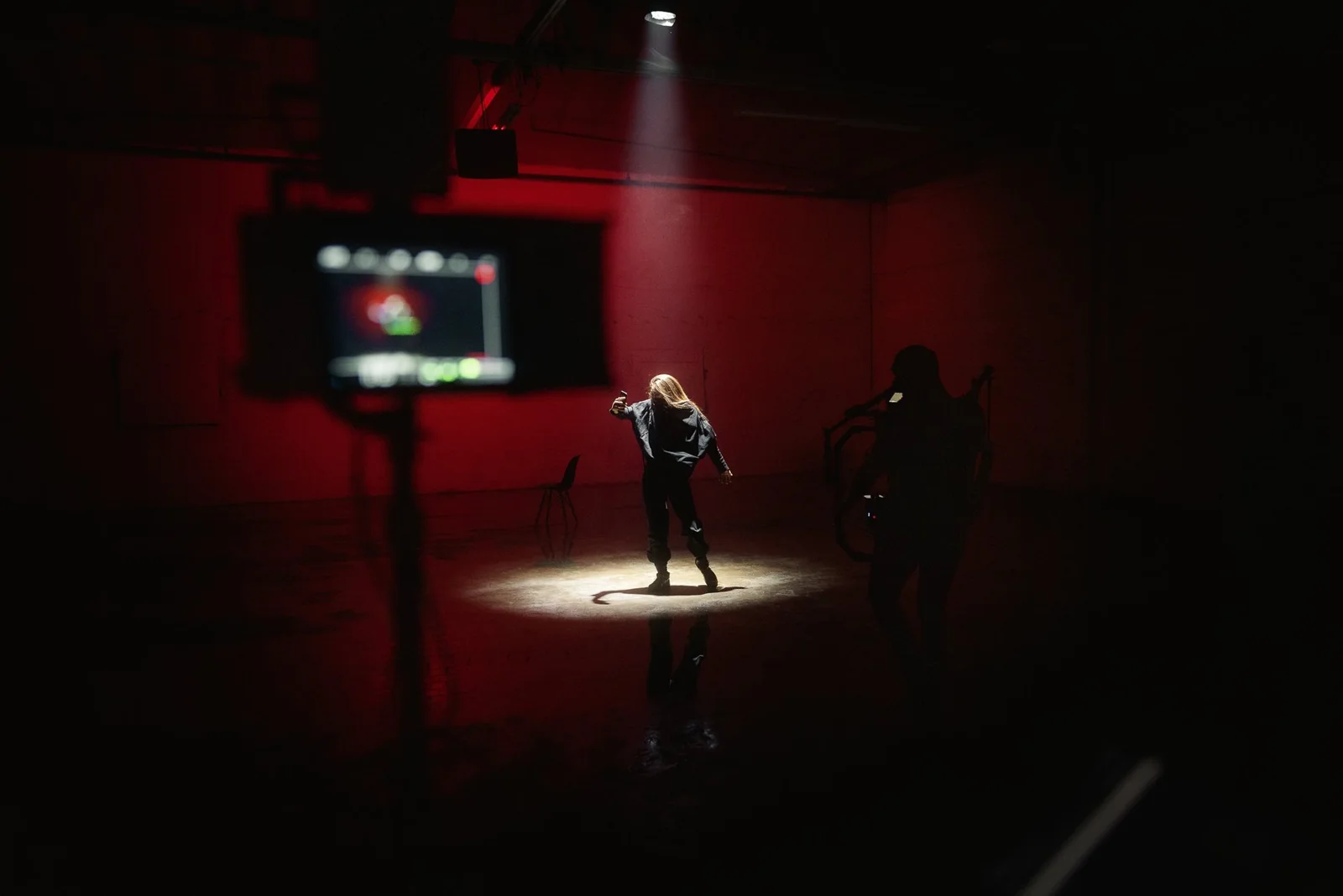 A performer in a spotlight on a red-lit set for Daktyl's Hyperion