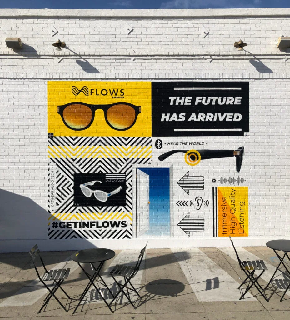 A Flows sunglasses mural on a white wall above cafe tables