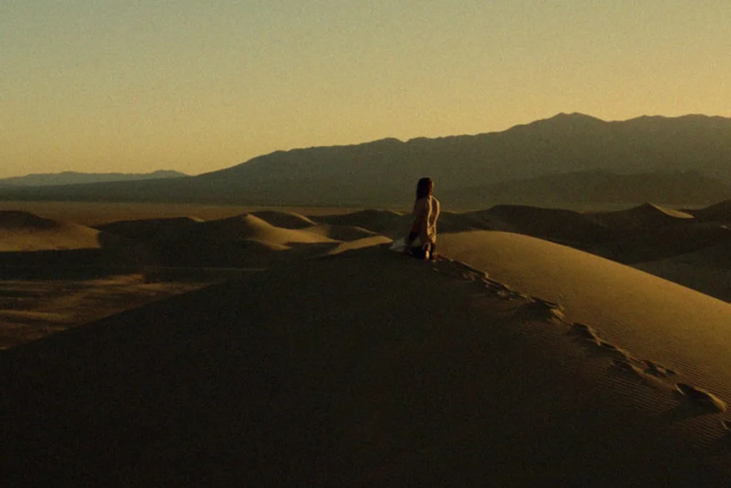 A lone figure on a sand dune at dusk