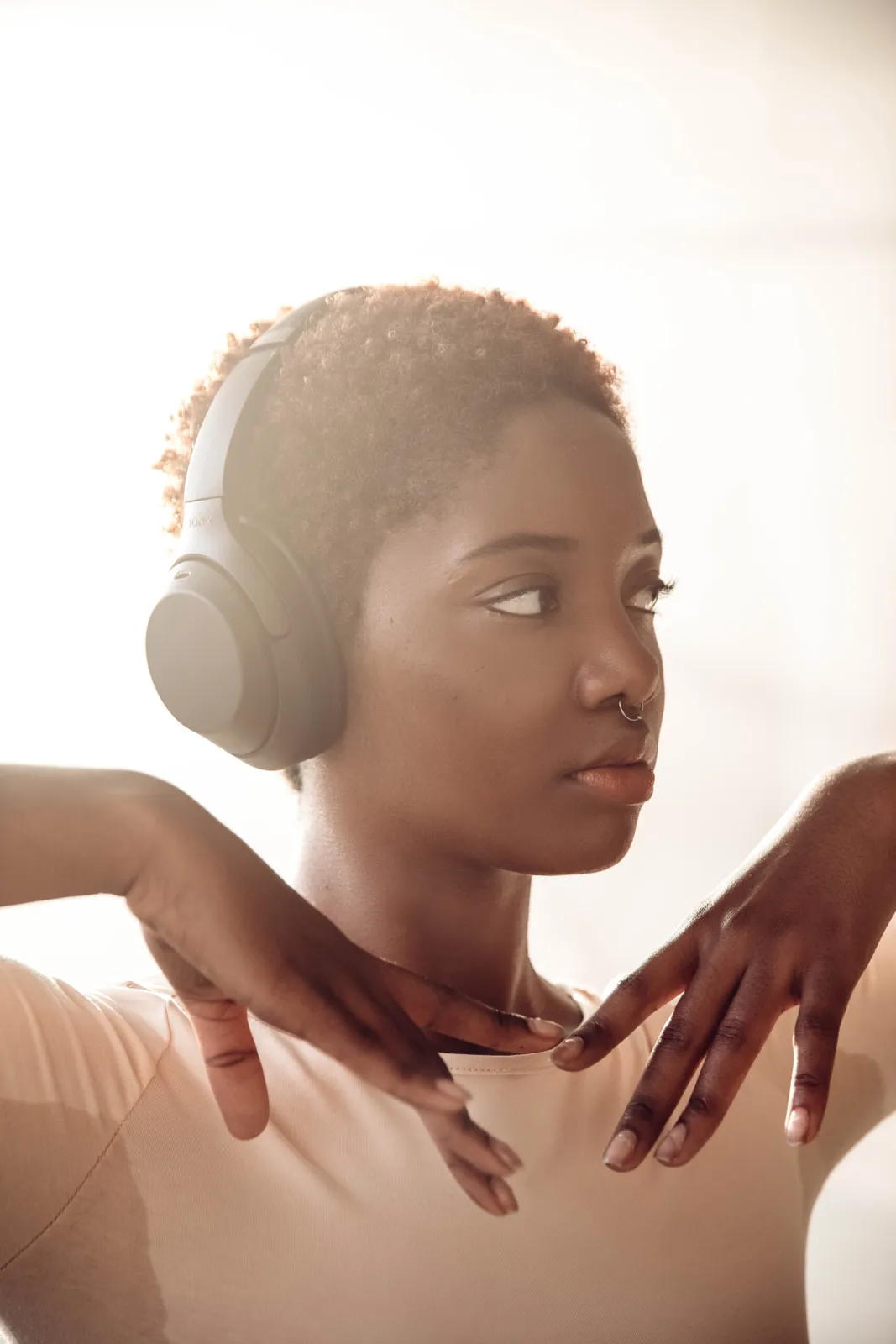 A dancer wearing Sony headphones in soft window light