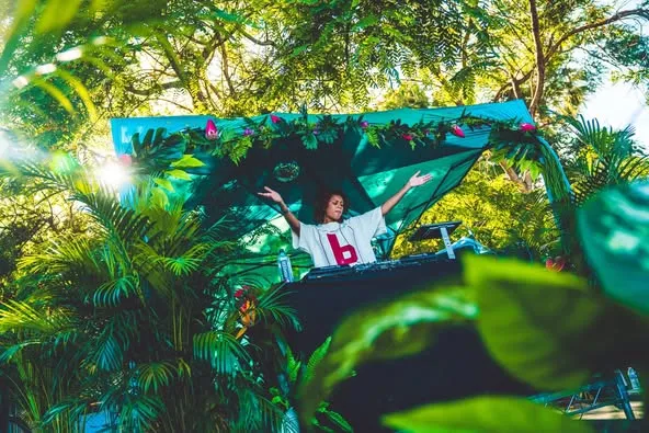 A DJ booth framed by palm leaves at SamJam