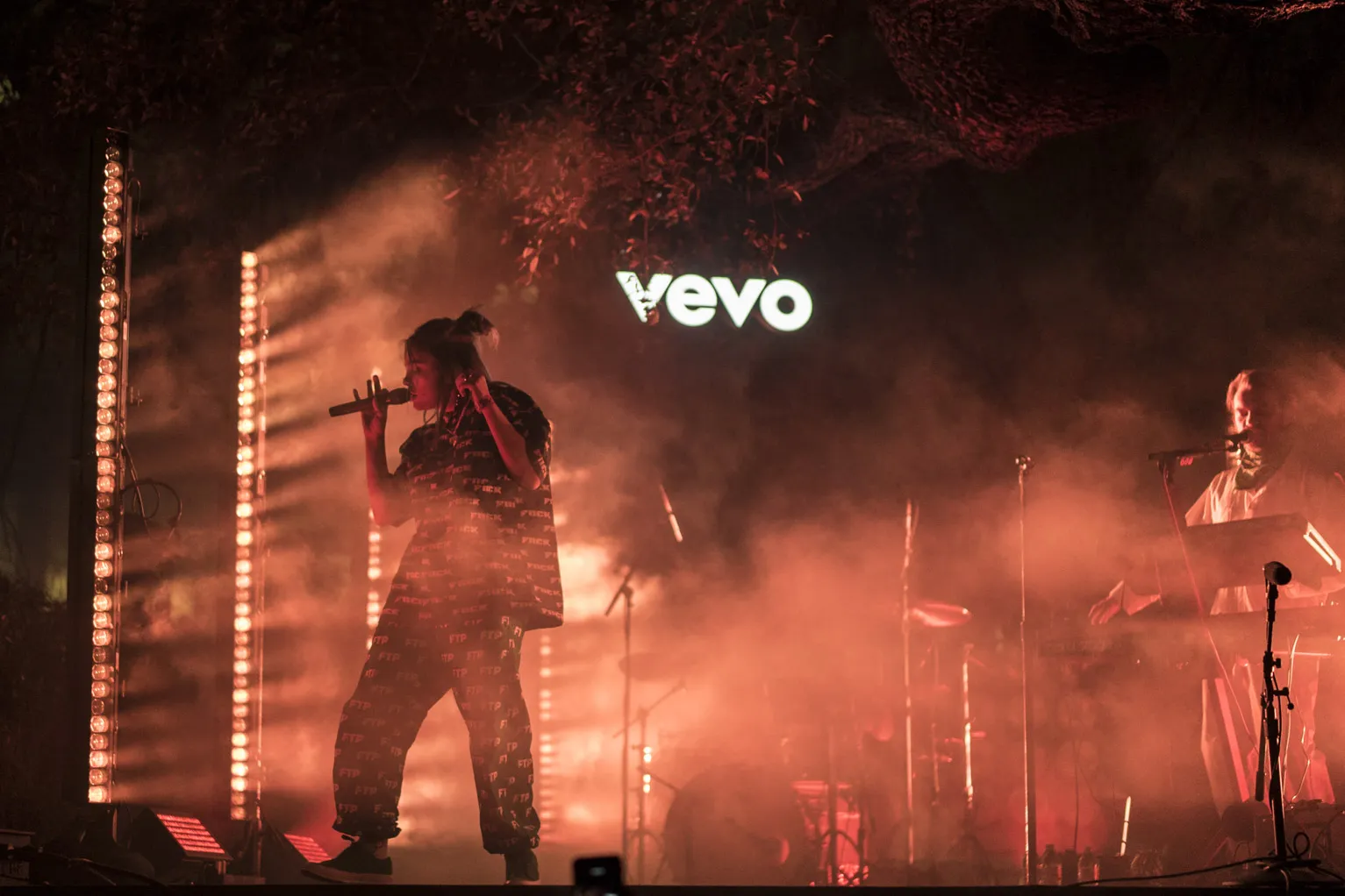 A singer on stage in red haze in front of a Vevo sign at SXSW