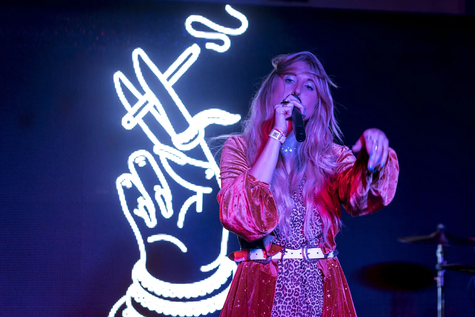 A singer in front of a neon hand sign at SXSW