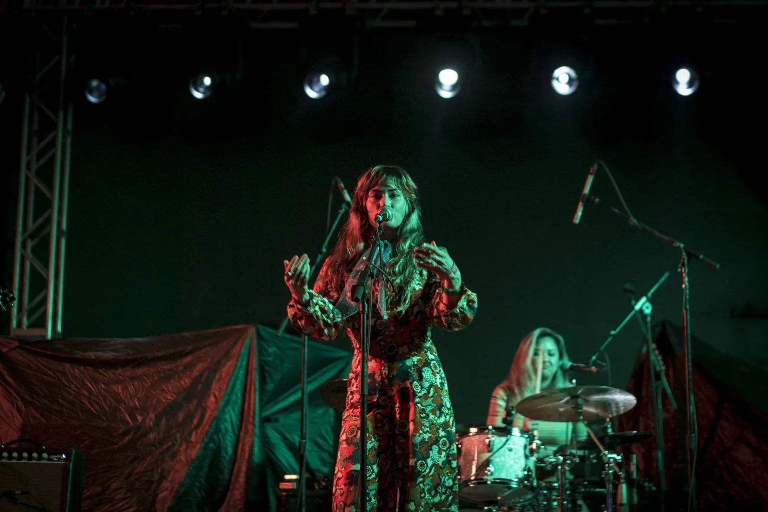 A singer and drummer on a dark stage at SXSW