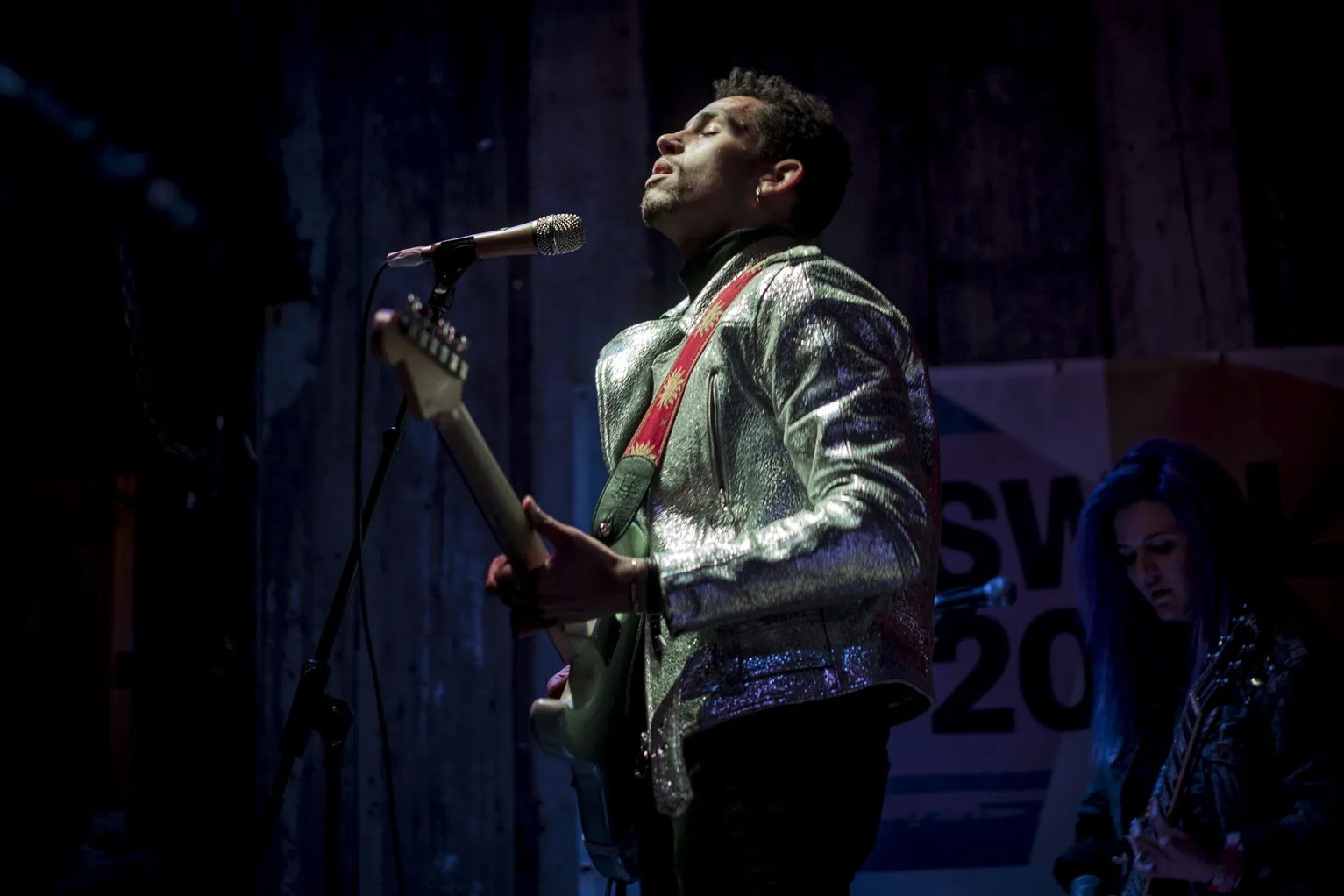 A guitarist in a silver jacket singing at SXSW