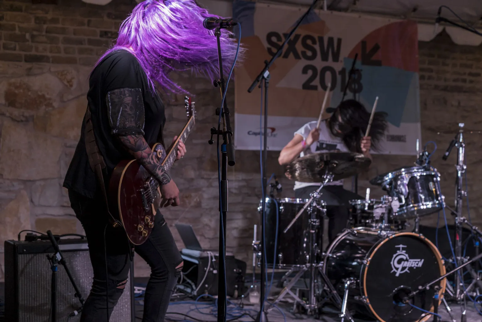 A guitarist with purple hair under the SXSW 2018 banner