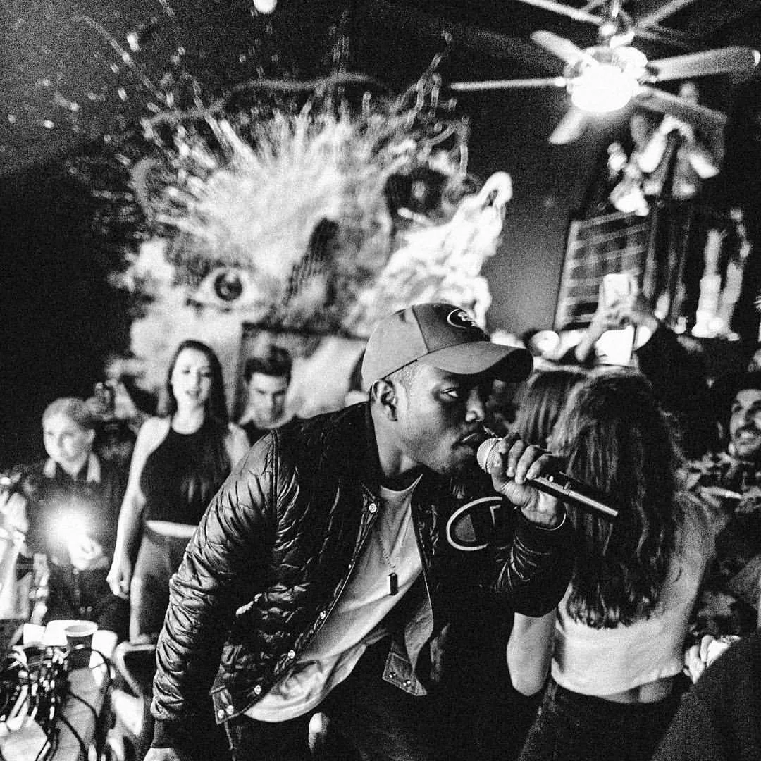 A performer with a microphone in a crowd at Winston House